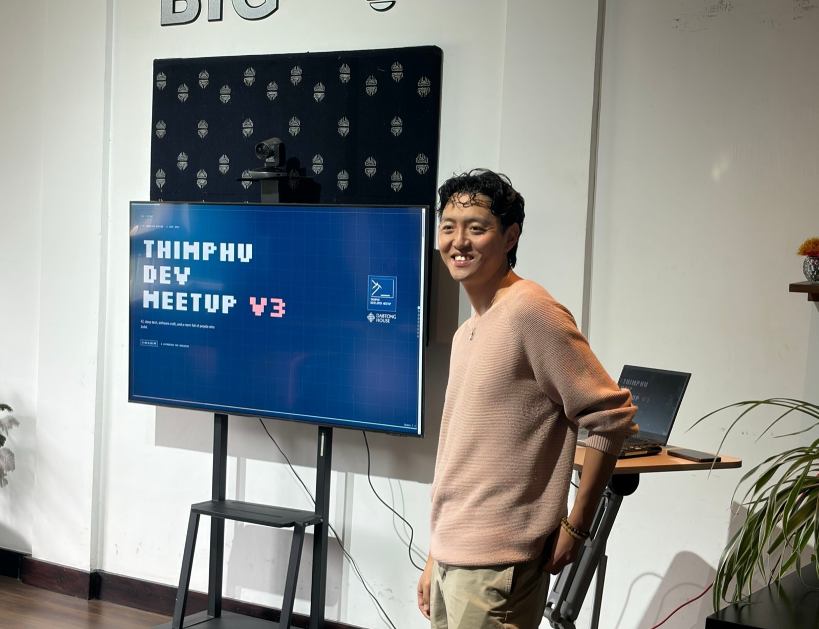 A speaker beside the Thimphu Dev Meetup V3 title slide