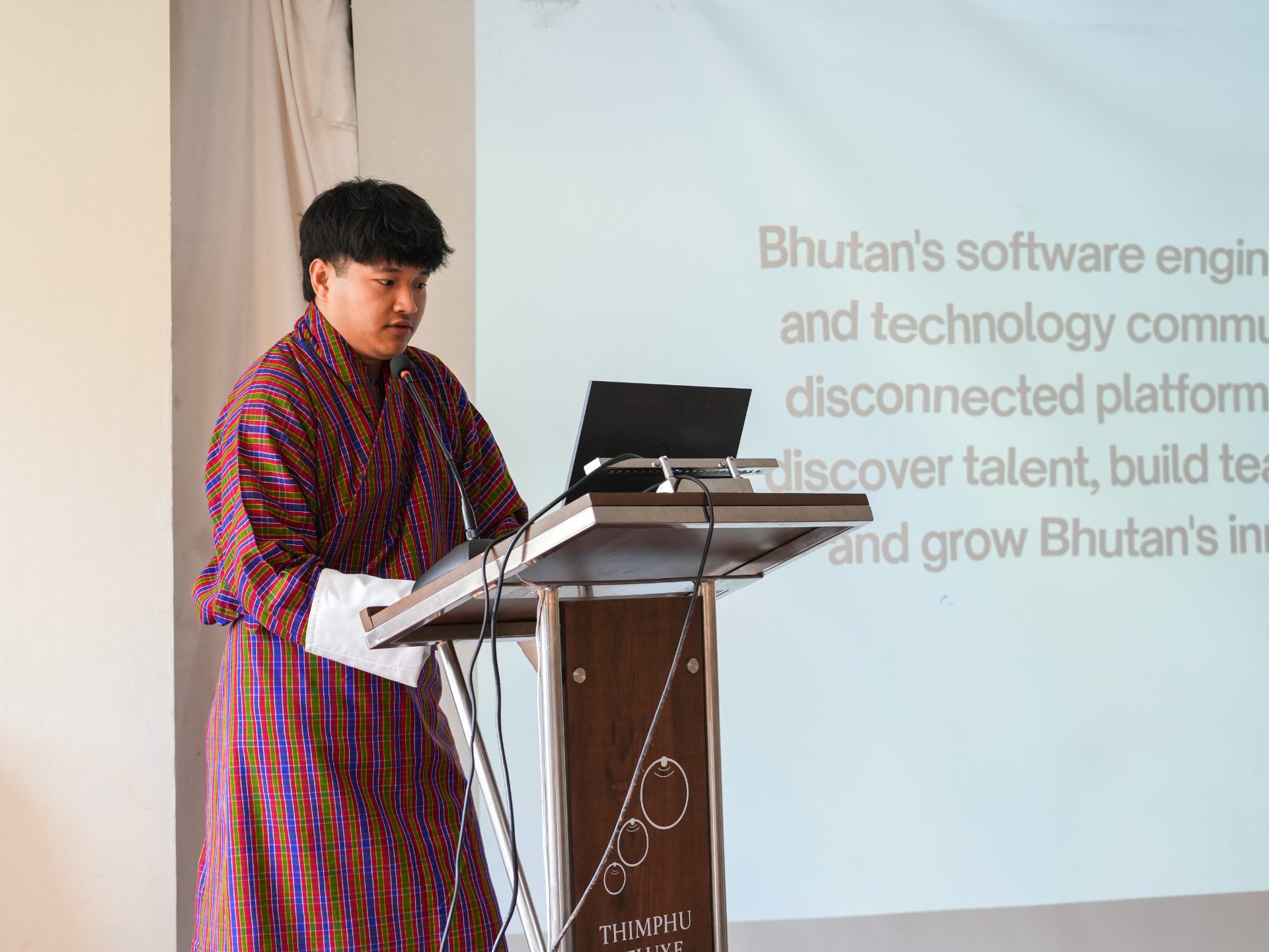 A speaker in a gho presents at AI Studio in Thimphu